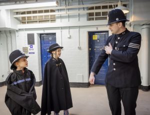 two children dressed in police uniform look at a volunteer dressed in Victorian police uniform