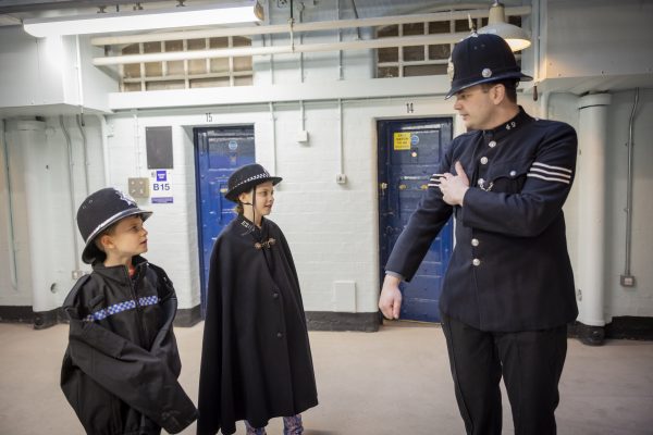 two children dressed in police uniform look at a volunteer dressed in Victorian police uniform