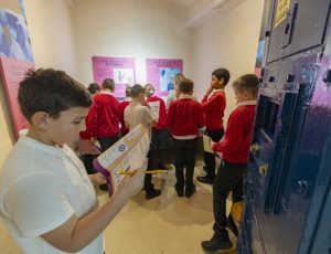 a group of school children in the forensics display room, working on their forensics trail