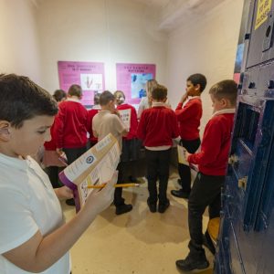 a group of school children in the forensics display room, working on their forensics trail