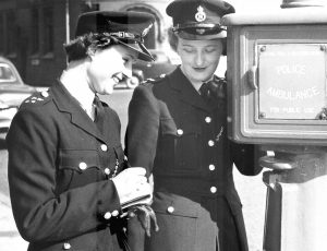 two birmingham city female police offices stand next to a police phone post circa 1950s