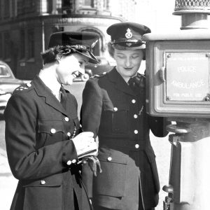 two birmingham city female police offices stand next to a police phone post circa 1950s