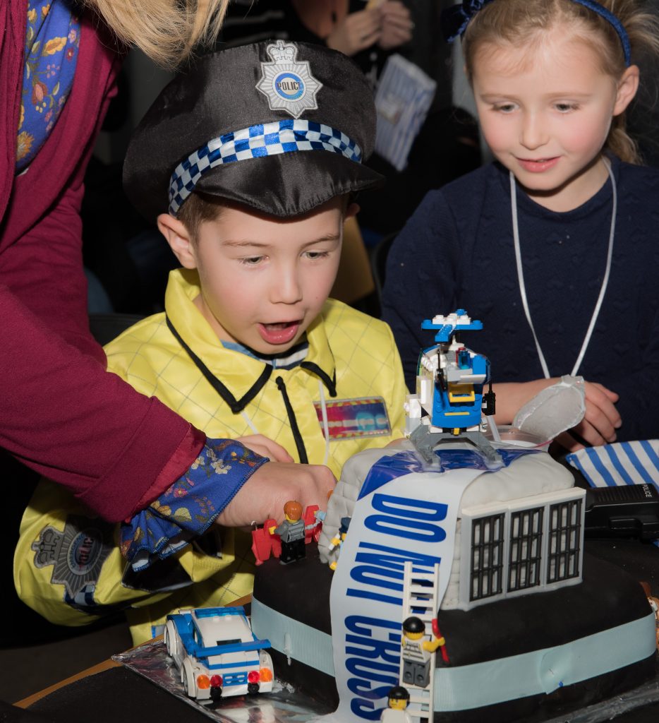 image of a boy dressed as a police officer with a police themed birthday cake