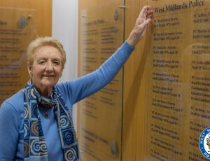 Linda pointing to the roll of honour where her late-husband is remembered