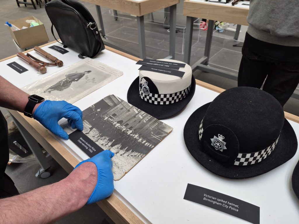 a curator arranges items and their descriptive text in a display case